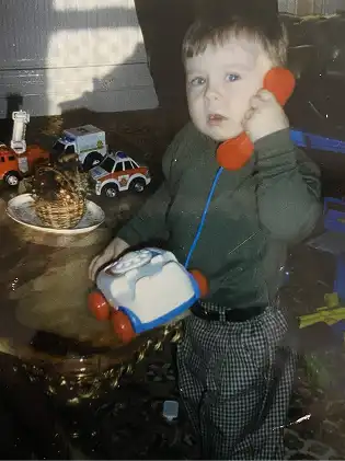 A young Marc answering a toy telephone